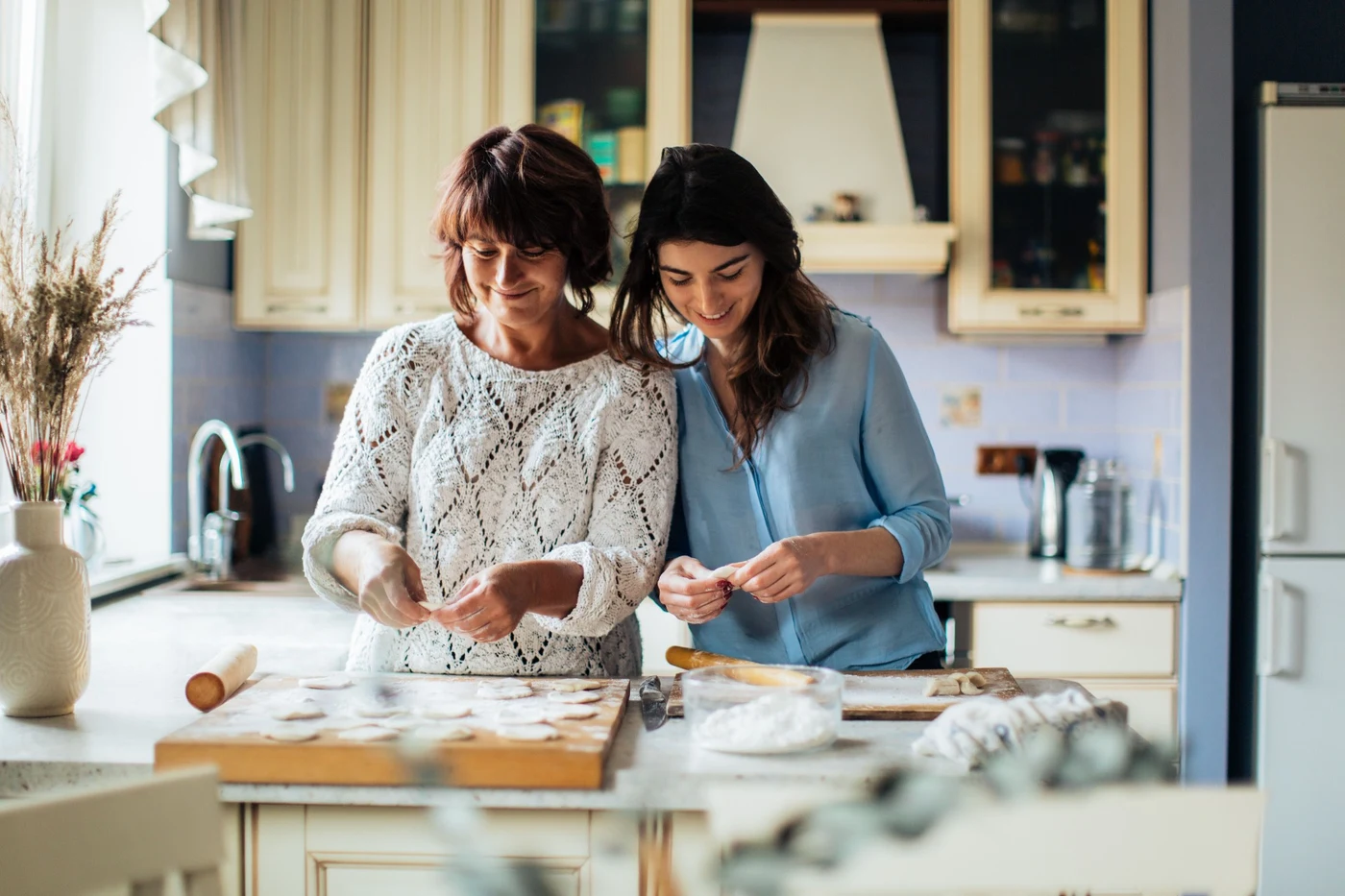 Two women making dumplings together in a home kitchen.