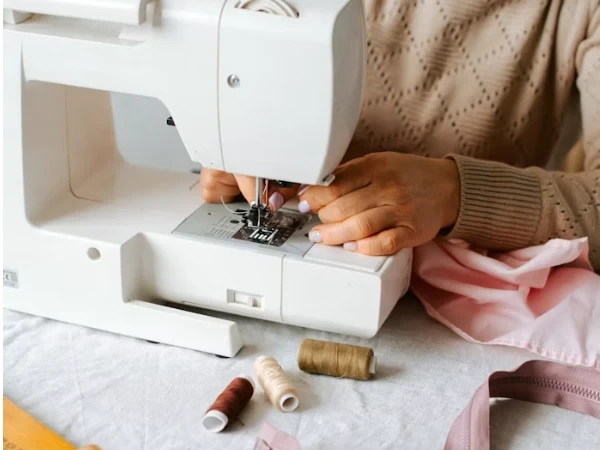 Hands working with fabric beside a sewing machine.
