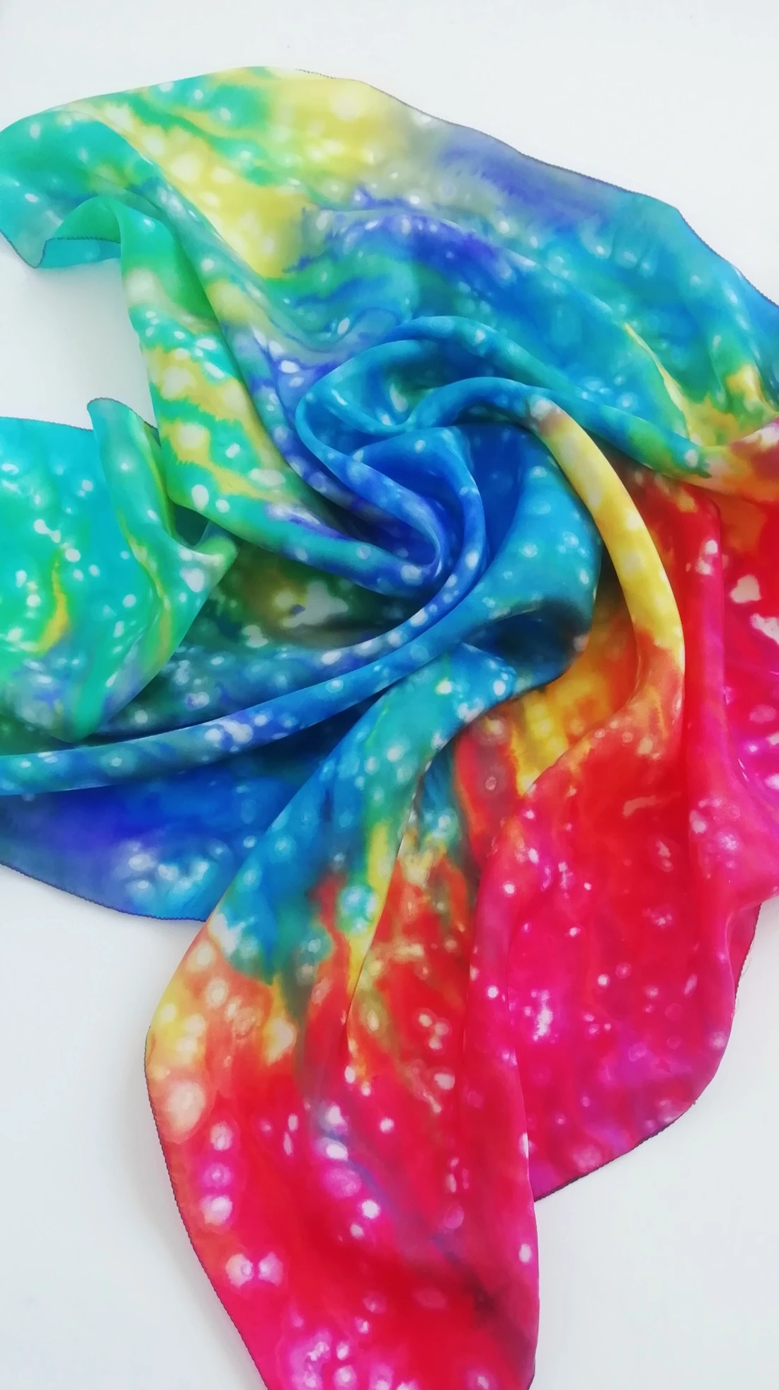 A hand painted silk scarf in bright turquoise, blue, yellow, red and pink.