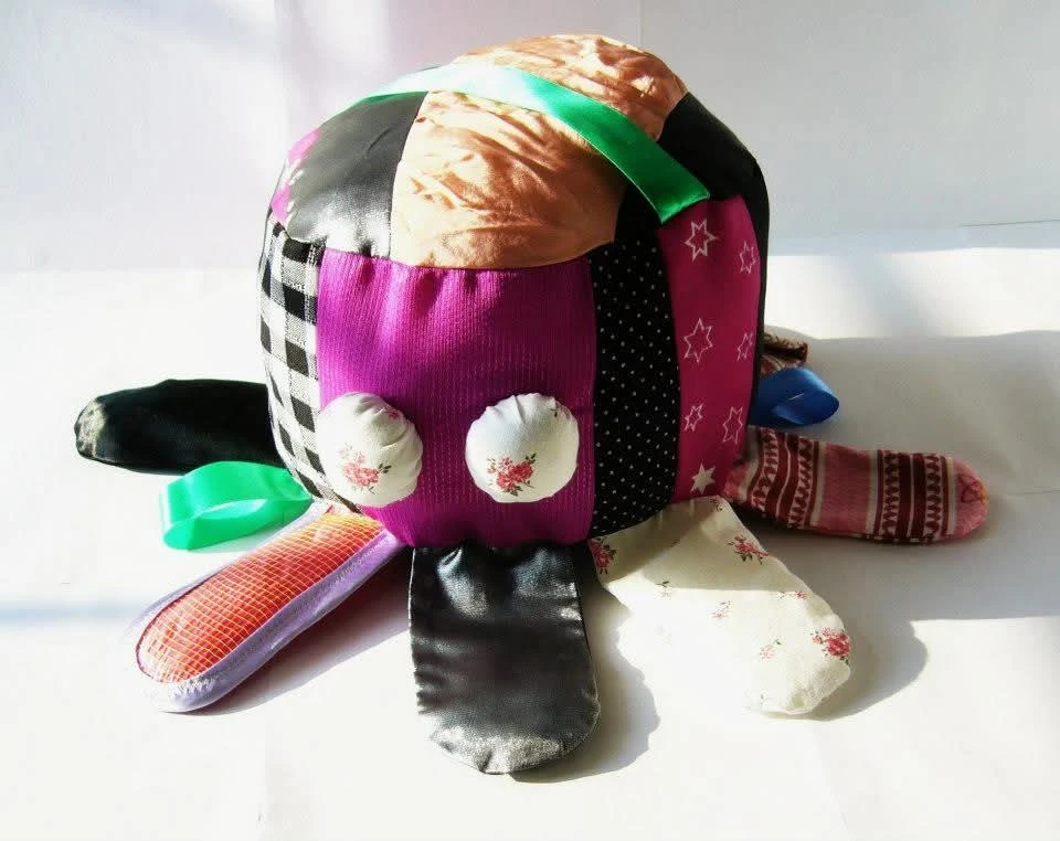 A handmade patchwork soft toy sewn from brightly coloured fabric scraps and ribbons.
