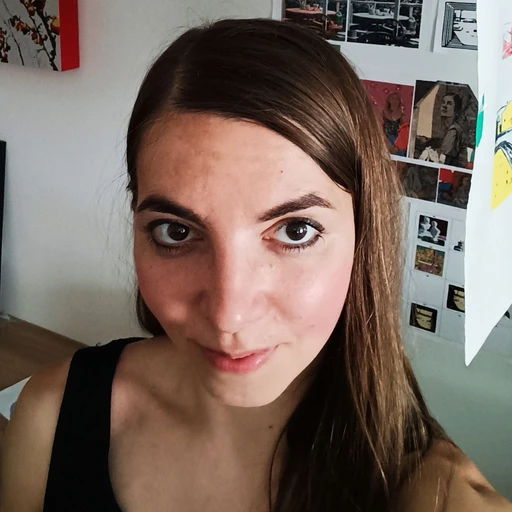 Ania in her studio, with paintings and prints on the wall behind her