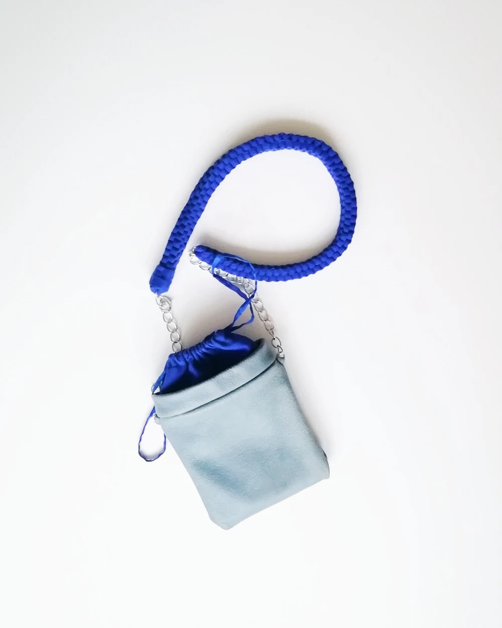 Small handmade blue and grey bag with a woven blue strap and silver chain.